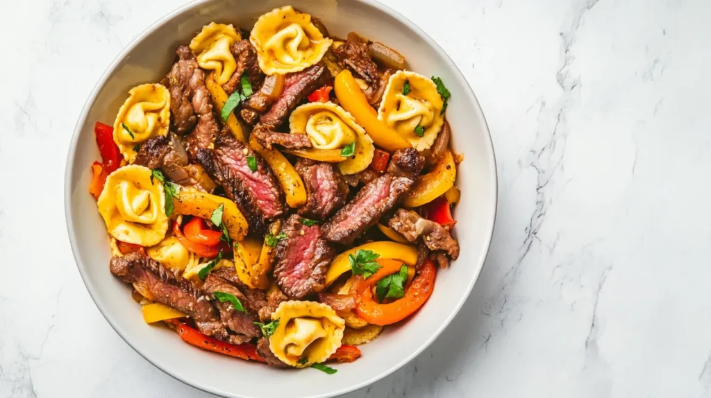 A comforting bowl of cheesesteak tortellini with bell peppers and onions.